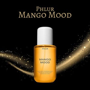 May include: A bottle of Phlur Mango Mood hair and body fragrance mist. The bottle is rectangular with rounded edges, filled with a golden-orange liquid, and topped with a white cap. The product name is printed in a bold, modern font. The background is black with gold sparkles.