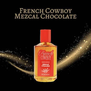 以下が含まれることがあります： 赤いキャップと「French Cowboy Mezcal Chocolat」と書かれた長方形のラベルが付いた香水瓶。ボトルには金色の液体が入っています。背景は黒で、金色のグリッターが付いています。