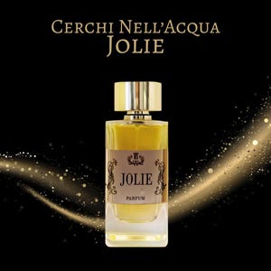 以下が含まれることがあります： 金色のキャップと長方形の透明なガラスベースが付いた香水瓶。ラベルには「Jolie Parfum」と装飾的な詳細が記載されています。背景は黒で、金色のグリッターアクセントがあり、上部には「Cerchi Nell'Acqua Jolie」というテキストがあります。