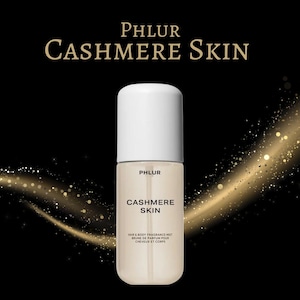 May include: A perfume bottle with a white cap and a beige body, labeled "PHLUR CASHMERE SKIN." The bottle is set against a black background with gold glitter accents. The text "HAIR & BODY FRAGRANCE MIST" is also visible.