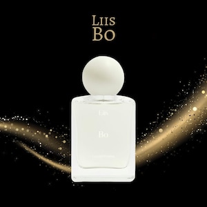 May include: A clear glass perfume bottle with a white spherical cap. The bottle has a rectangular shape with rounded corners. The text "Liis Bo" is printed on the bottle and above it. The background is black with gold sparkles.