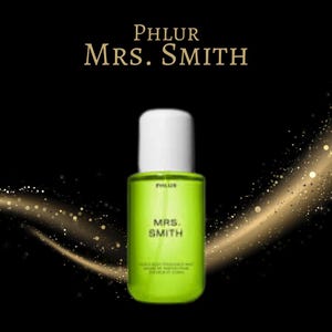 May include: A neon green perfume bottle with a white cap. The bottle has the text "PHLUR MRS. SMITH" in white. The background is black with gold glitter accents.