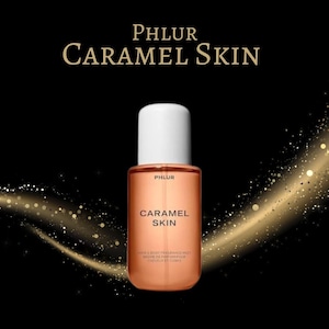 May include: A bottle of Phlur Caramel Skin fragrance. The bottle is a rectangular shape with a white cap and a caramel-colored liquid inside. The words "Phlur" and "Caramel Skin" are printed on the bottle. The background is black with gold sparkles.