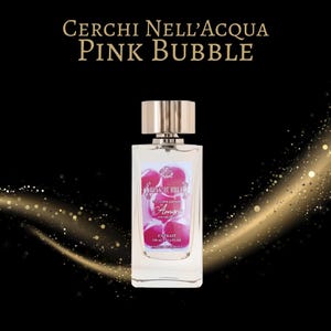 May include: A rectangular perfume bottle with a silver cap and a pink label. The label features the text "PINK BUBBLE" and "Amyris". The bottle contains a clear liquid and is set against a black background with gold sparkles. The bottle is 100 ml / 3.4 fl. oz.
