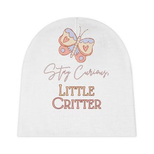 May include: White baby beanie featuring a butterfly illustration in pastel colors. The text "Stay Curious, LITTLE CRITTER" is printed below the butterfly. The beanie is designed for infants and toddlers.