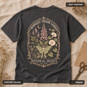 Pepper Comfort Colors T-shirt flatlay showing the large vintage poison garden and luna moth back design.