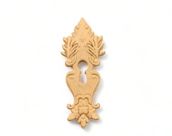 May include: A gold-colored keyhole cover with intricate floral designs. The cover is made of metal and has a classic, ornate style.