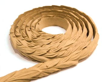 May include: A coiled length of decorative trim with a leaf pattern. The trim is a light brown color and has a textured surface.