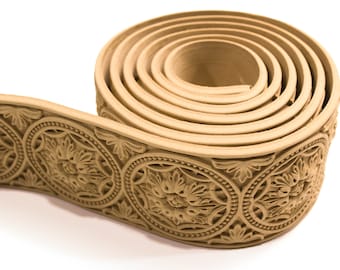 May include: A tan-colored decorative trim with a repeating pattern of circular designs. The trim is rolled up and the pattern is visible on the outside of the roll.
