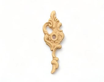 May include: A gold-colored metal decorative accent piece with a floral design. The piece has a hole in the center and a long, thin stem.