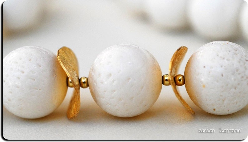 Puede incluir: Un collar de perlas blancas con detalles dorados. Las perlas son redondas y tienen una superficie texturizada. Los detalles dorados son peque&ntilde;os y delicados.