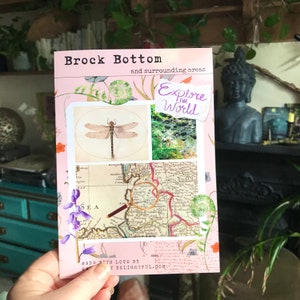 May include: A pink postcard with the text "Brock Bottom and surrounding areas" and "Explore the World". The postcard features a dragonfly illustration, a photo of a stream, a vintage map with a magnifying glass, and floral designs.
