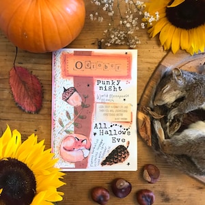 Peut inclure: Un livre brun et orange avec le titre "October Punky Night World Menopause Month" et le texte "A11. Hallows Eve" sur la couverture. Le livre est entouré d'objets d'automne, dont une citrouille, des tournesols, des glands et un écureuil endormi.