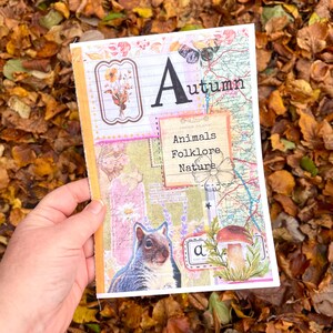 Peut inclure: Un journal avec le mot "Autumn" et la lettre "A" imprimés sur la couverture. Le journal présente des images d'un écureuil, d'un champignon et d'un papillon. Les mots "Animals", "Folklore" et "Nature" sont également imprimés sur la couverture.