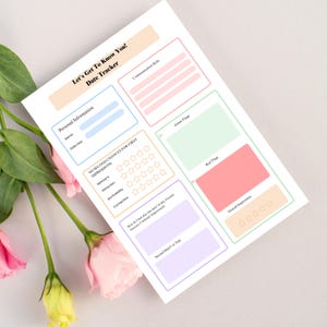 May include: A white date tracker with pastel-colored boxes and the text "Let's Get To Know You! Date Tracker." The tracker includes sections for personal information, impressions, and communication style. Pink and yellow flowers are in the foreground.
