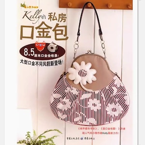 Peut inclure: Un sac à main en tissu rayé marron et blanc avec une applique de fleur blanche. Le sac à main a une bandoulière en cuir marron et une chaîne en métal. Le sac à main est étiqueté "Kelly's Private Room Mouth Gold Bag" en caractères japonais et chinois. Le texte indique également "Collection de 8,5 cm de bouche en or !" et "Nouvelle sortie de différents styles de bouche en or de grande taille !"