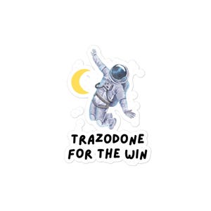 May include: A sticker featuring an astronaut floating in space with a crescent moon in the background. The text "Trazodone for the win" is printed below the astronaut.
