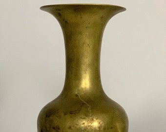May include: A gold-toned brass vase with a wide, flared opening and a rounded body. The vase has a smooth, polished finish and a slightly flared base.