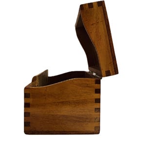 May include: A wooden box with a hinged lid, open to reveal the interior. The box is constructed with dovetail joints and features a warm, natural wood grain. The lid has a curved design.