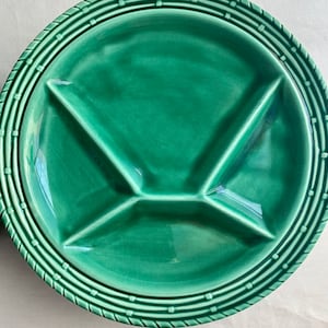 May include: A green ceramic divided serving plate with a raised rim and a decorative border. The plate is divided into four sections.