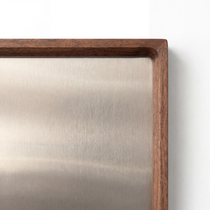 Close-up of the upper right corner of the walnut wood frame and brushed metal surface of the magnetic board.