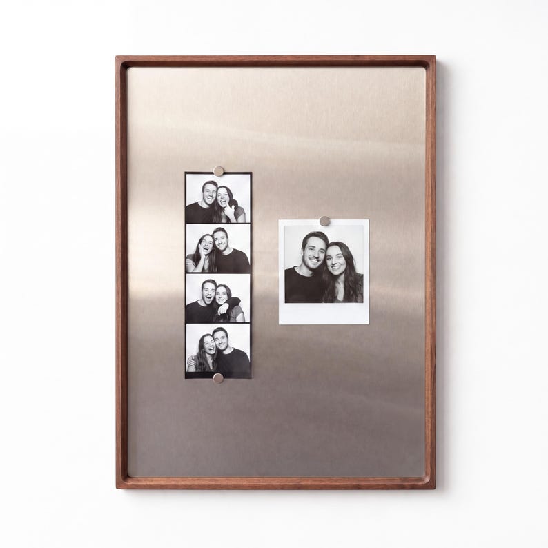Walnut-framed magnetic board featuring a photo strip and a square photo attached with small magnets.