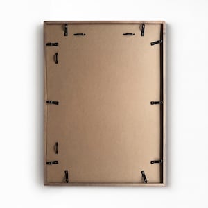 Back view of the framed magnetic board showing the brown backing board and multiple black mounting clips.