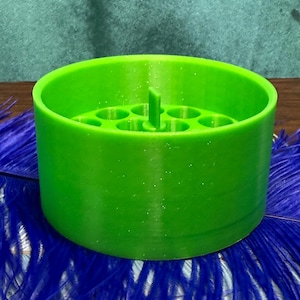 May include: A bright green plastic organizer with multiple circular compartments for storing small items. The organizer has a central divider and a textured surface.