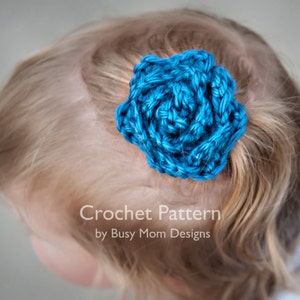 May include: A blue crocheted flower hair clip. Crochet Pattern by Busy Mom Designs.