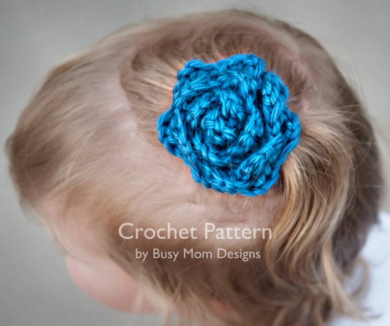 May include: A blue crocheted flower hair clip. Crochet Pattern by Busy Mom Designs.