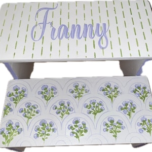 May include: A white wooden step stool with a purple and green floral design on the top step and the name "Franny" written in purple on the bottom step.