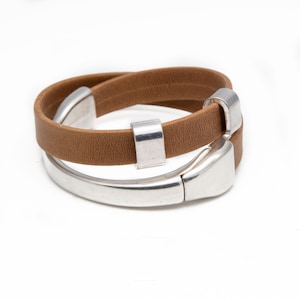 Op de afbeelding: Een bruine leren wikkelarmband met zilverkleurige metalen details. De armband heeft een dubbel wikkelontwerp met een magnetische sluiting. Het leer is lichtbruin van kleur.