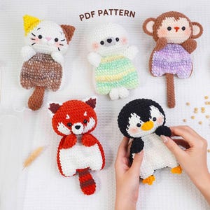 May include: A collection of handmade crochet animal toys, including a cat, a red panda, a monkey, a penguin, and a seal. The toys are in various colors, such as brown, white, red, and black. The text "PDF PATTERN" is visible in the image.