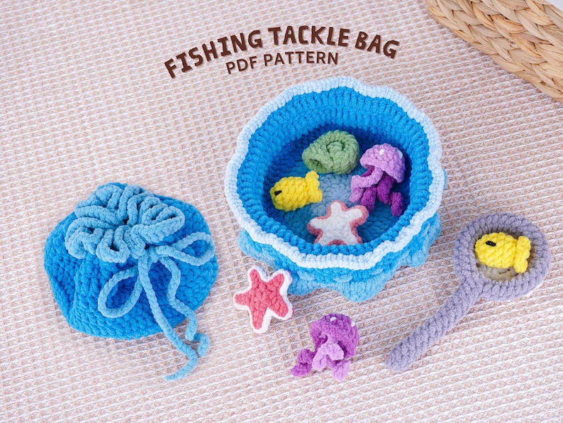 May include: A crocheted fishing tackle bag set with a blue drawstring bag, a blue bowl with sea creature toys, and a magnifying glass with a yellow fish. The set includes a starfish, jellyfish, and fish. The text "FISHING TACKLE BAG PDF PATTERN" is at the top.