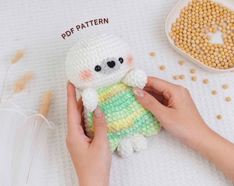 May include: A handmade crochet doll with a white head, gray face, and pink cheeks. The doll has a green and yellow striped body and white arms and legs. The text "PDF PATTERN" is in the upper left corner.