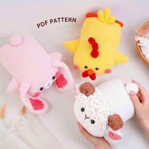 Op de afbeelding: Drie gebreide knuffels: een roze konijn, een gele kuiken en een wit lam. Het konijn heeft roze oren, de kuiken een rode kam en het lam bruine oren. De tekst "PDF PATTERN" is zichtbaar.