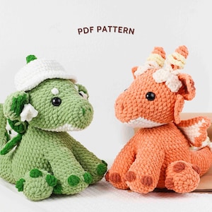 May include: Two crocheted dragon plushies. One is green with a white hat, the other is orange with white and yellow accents. Both have large black eyes and are sitting down. The text "PDF PATTERN" is above them.