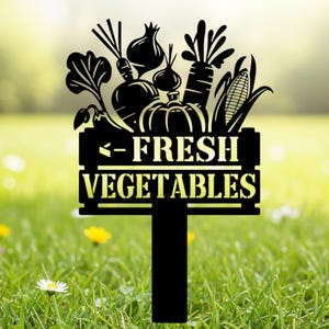May include: Black metal garden stake featuring a silhouette of various vegetables, including carrots, onions, and a pumpkin, above the words "FRESH VEGETABLES". The stake is designed to be placed in a garden or vegetable patch.