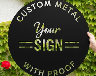 Può includere: Un cartello rotondo in metallo nero con le scritte bianche "CUSTOM METAL" e "Your SIGN WITH PROOF". Il cartello è tenuto contro uno sfondo di fogliame verde e rose rosse.