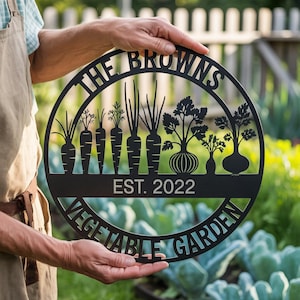 Puede incluir: Letrero de jardín de metal negro con las palabras "THE BROWNS" y "VEGETABLE GARDEN". El letrero presenta siluetas de verduras, incluyendo zanahorias y cebollas, con "EST. 2022" debajo. El letrero es redondo.