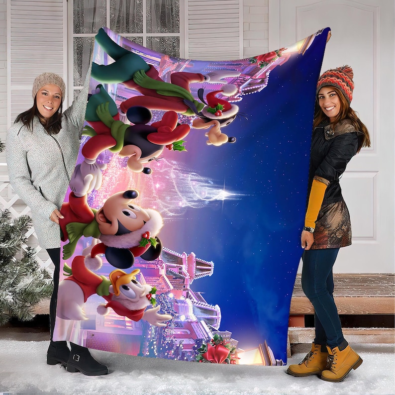 May include: A colorful Christmas-themed blanket featuring Mickey Mouse, Goofy, and other Disney characters. The blanket has a vibrant design with a blue night sky background and festive decorations. The blanket is held by two people.
