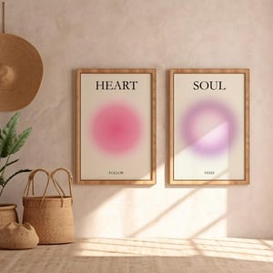May include: Two framed prints with a minimalist design. The print on the left has a pink gradient circle with the word "HEART" above it. The print on the right has a purple gradient circle with the word "SOUL" above it.