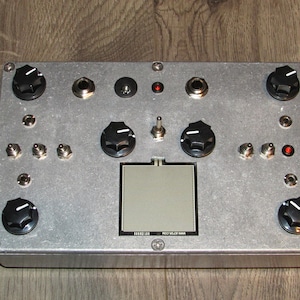May include: A silver metal box with a gray screen, multiple knobs, and jacks. The box has the text "PRO VIDEO MIXER" printed on it.