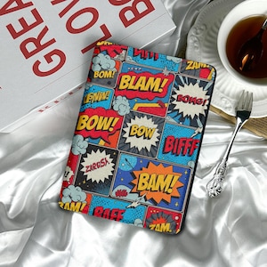 May include: A colorful tablet case with a comic book design. The case features speech bubbles with action words like "BLAM!" and "BAM!" in bold, vibrant colors. The background is a mix of blue, red, and yellow.