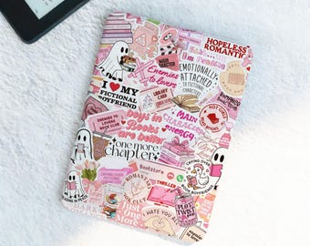 May include: A white and pink Kindle case covered in stickers with phrases like "I love my fictional boyfriend" and "Enemies to Lovers." The case features ghost illustrations, book graphics, and the words "Book Club."