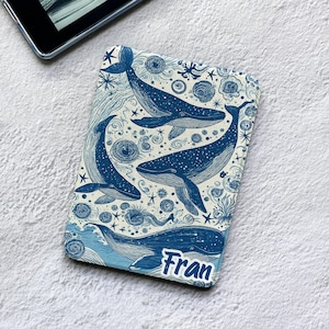 May include: A rectangular e-reader case featuring a blue and white illustration of multiple whales swimming among stars, swirls, and sea life patterns. The name Fran is printed in a bold blue font at the bottom right corner of the cover.