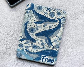 Könnte beinhalten: Eine rechteckige E-Reader-Hülle mit einer blau-weißen Illustration von mehreren Walen, die zwischen Sternen, Wirbeln und Meereslebewesen schwimmen. Der Name Fran ist in einer fetten blauen Schrift unten rechts auf der Hülle aufgedruckt.