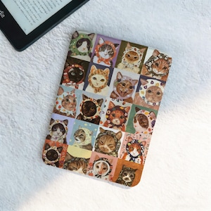 Op de afbeelding: Een kleurrijke Kindle-hoes met een raster van kattenportretten. Elke kat draagt een andere patroonkap of muts. De hoes is rechthoekig en ligt op een wit, getextureerd oppervlak.