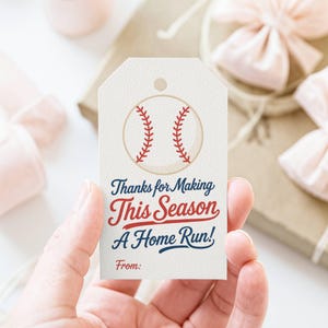 以下が含まれることがあります： 野球をテーマにしたギフトタグ。野球のグラフィックと「Thanks for Making This Season A Home Run!」のテキストが赤と青で描かれています。タグはクリーム色です。