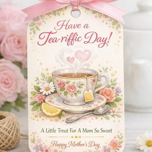 Könnte beinhalten: Ein Geschenk-Anhänger mit einer rosa Schleife zeigt eine Aquarell-Illustration einer Teetasse mit Rosen, einer Zitronenscheibe und dem Text "Have a Tea-riffic Day!" und "Happy Mother's Day."